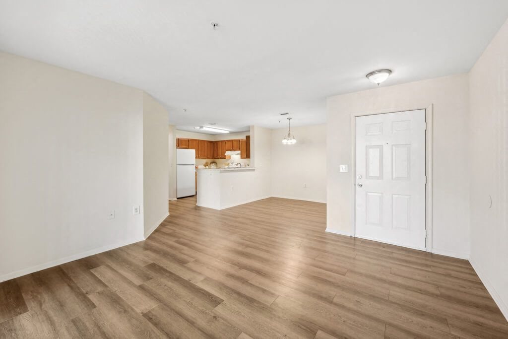 an empty living room and kitchen with a white door